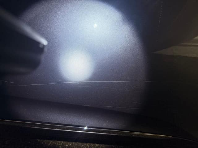 Scratches on a side door under a flashlight, before